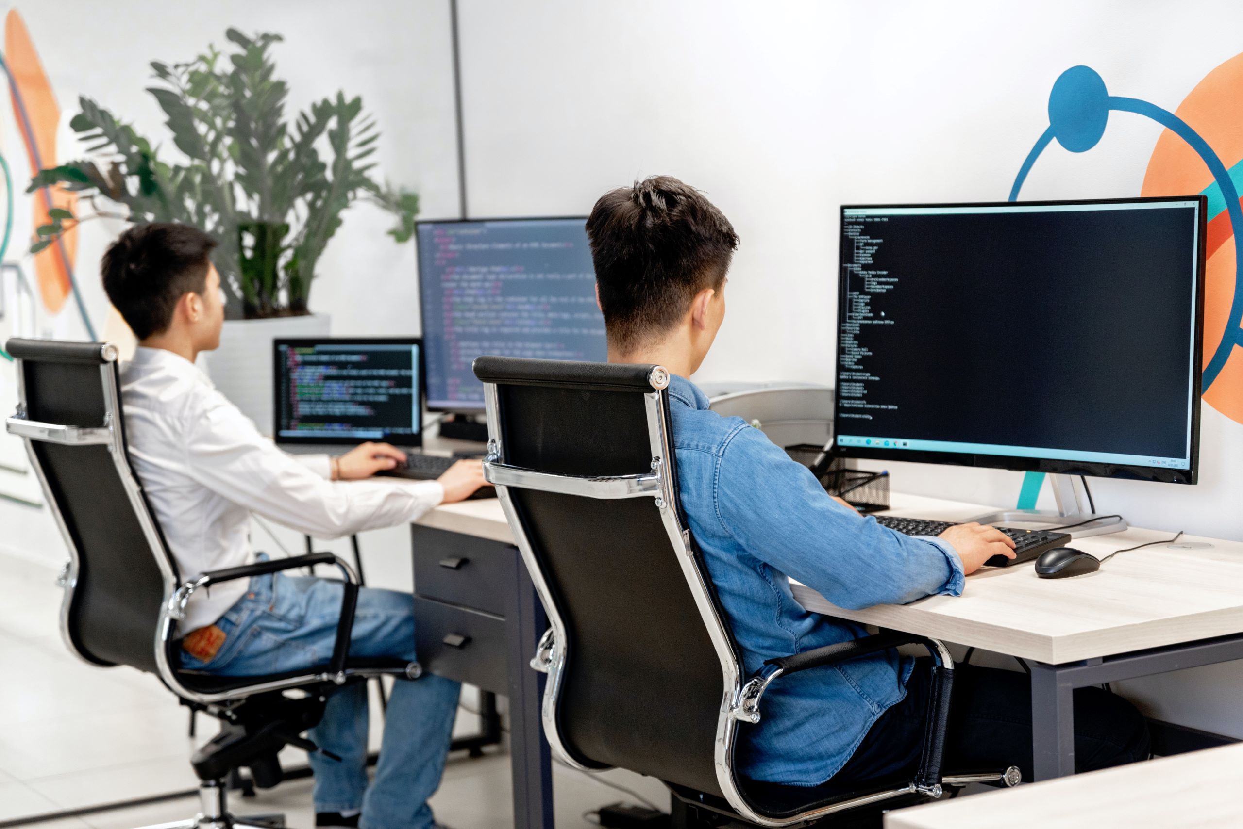 Two people sitting at their desks working on computers.